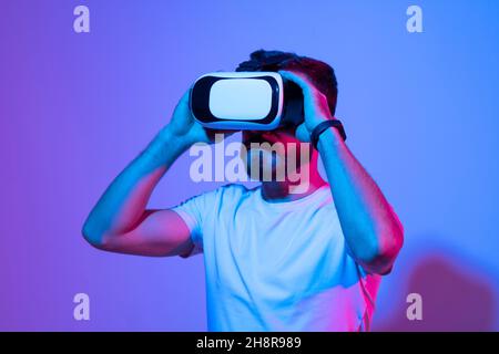 Closeup of young man wearing virtual reality goggles in modern studio. Smartphone using with VR headset. Stock Photo