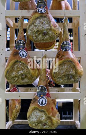 Tuttofood fair, Milan, Italy - 25 october 2021: Italian hams hanging to ripen in a wooden shelf Stock Photo