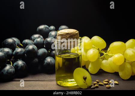 Grape oil seed in small vintage bottle. Heap of grape seeds with green slices and cold press organic essential oil, tincture, extract, infusion on Stock Photo