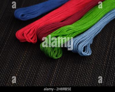 Colorful cross stitch embroidery threads on a black background. Close up. Stock Photo