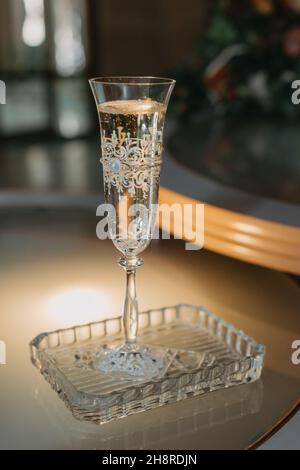 A WEDDING GLASS OF CHAMPAGNE STANDS ON THE TABLE IN A CRYSTAL PLATE. Stock Photo