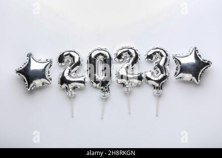 Figure 2023 and star shaped balloons on light background Stock Photo