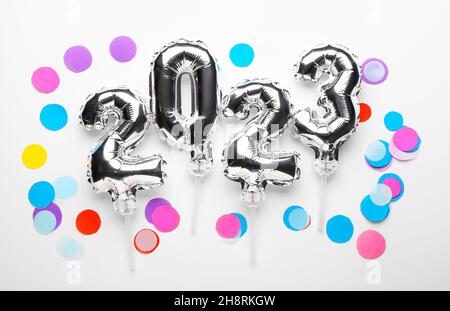 Figure 2023 made of silver balloons and confetti on light background Stock Photo