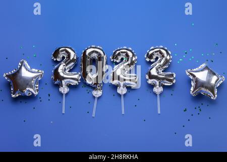 Figure 2022 and star shaped balloons on blue background Stock Photo