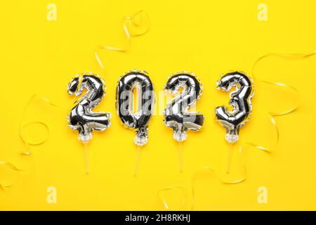 Figure 2023 made of silver balloons and ribbons on yellow background Stock Photo