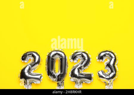 Figure 2023 made of silver balloons on yellow background Stock Photo