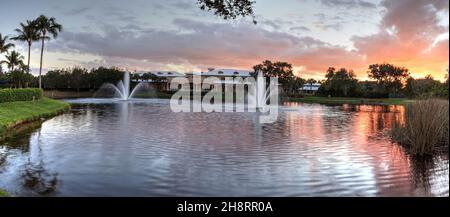 Two large fountains spout up from a tranquil pond in the tropics at sunset. Stock Photo