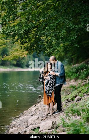 Man hugs the shoulders of a pregnant woman by the lake Stock Photo - Alamy