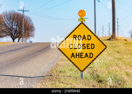Yellow road closed ahead sign on rural road. Road construction, repair and travel safety concept. Stock Photo