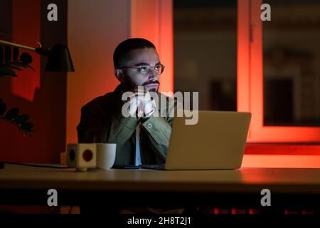 Pensive manager, web designer work late in empty closed coworking space. Overwork time and overtime Stock Photo