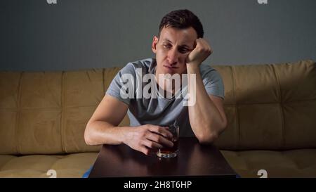 Young tipsy man drinks alcohol trying to solve problems Stock Photo