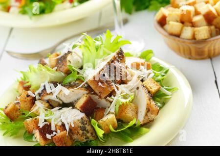 Caesar chicken salad with grated parmesan on white table Stock Photo