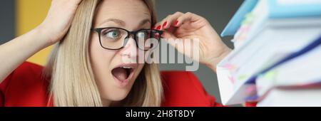 Scared young businesswoman secretary with huge stack of folders Stock Photo