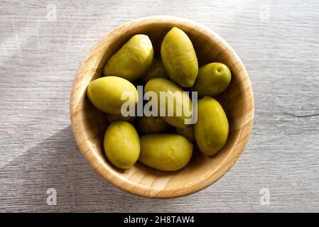 Bowl with Italian green olives from Cerignola. Bella di Cerignola Italian olives on wooden table. Top view Stock Photo