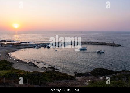 The sun sets over the small fishing harbour of Agios Georgios (St Georges) Paphos district, Cyprus Stock Photo