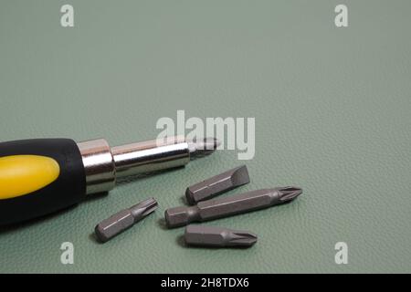 Screwdriver with a set of bits on a green background Stock Photo