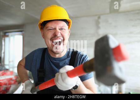 Builder man with a long hammer in his hands Stock Photo