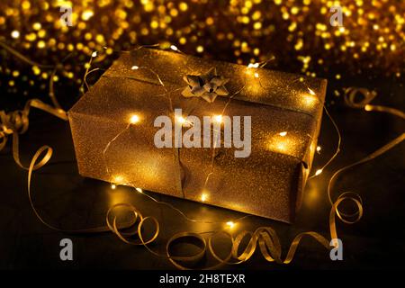 gold gift wrapped in string lights on golden bokeh background Stock Photo