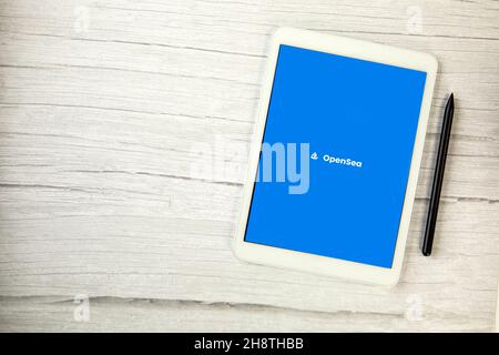 The Netherlands, December 2021 Opensea app on white digital tablet on wooden table with copy space, market place for non-fungible tokens NFT digital Stock Photo