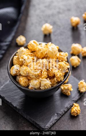 Sweet caramel popcorn in bowl on black table. Stock Photo