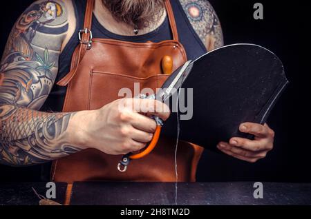 Currier of leather working with leather using crafting tools in his tanning shop Stock Photo