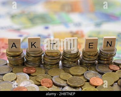 Coin stacks with letters AKTIEN, the German word for shares, on euro banknote background, concept of money investment Stock Photo