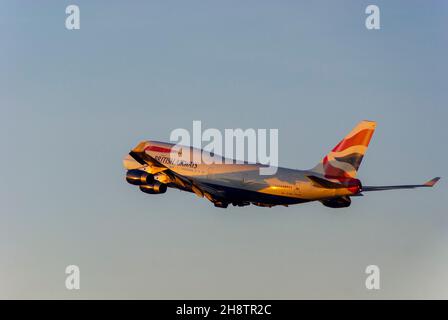 British Airways Boeing 747 Jumbo Jet airliner jet plane climbing after take off from London Heathrow Airport, UK, at dusk with warm glow from sunset Stock Photo
