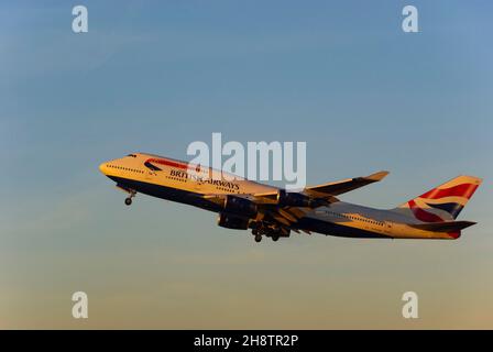 British Airways Boeing 747 Jumbo Jet airliner jet plane climbing after take off from London Heathrow Airport, UK, at dusk with warm glow from sunset Stock Photo