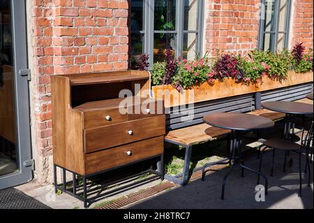 Old wooden wardrobe or cupboard of street cafe against the backdrop of an old brick wall with flowers on a sunny day Stock Photo