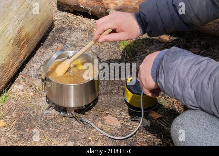 Camping food making. Tourist foods in outdoor activities. Soup in bowler in the forest for trevelers. Stock Photo