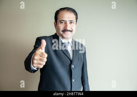 Smart mature older business man with moustache showing a thumbs up wearing suit and tie Stock Photo