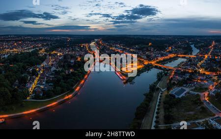Panorama of the city of Regensburg in Bavaria with the river Danube the illuminated cathedral and the stone bridge in summer at blue hour in twilight, Stock Photo