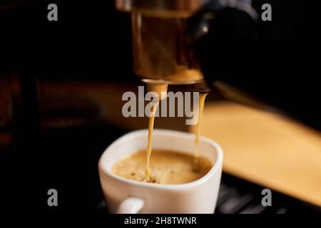 Detail of a professional coffe maker dripping coffe into an empty cup in a cafeteria, Machine is making a perfect coffee with delicious smell, . Espre Stock Photo