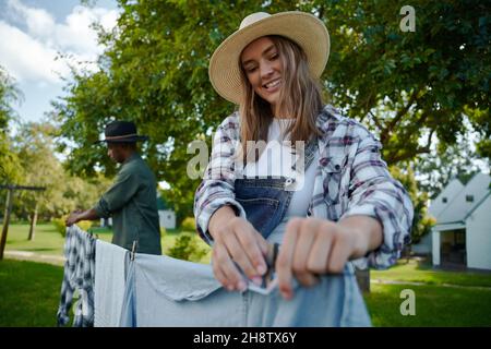 Caucasian female farmer pegging dirty laundry on washing line Stock Photo