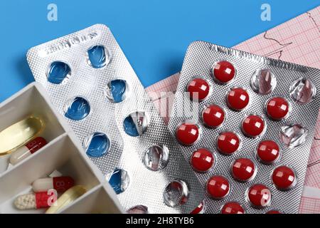 Medical cardiology concept. Heart health pills and cardiogram on a blue background. ECG. Copy space. Stock Photo