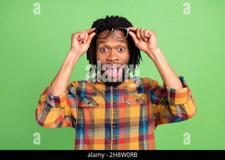 Photo of pretty impressed dark skin guy dressed checkered arms glasses open mouth isolated green color background Stock Photo