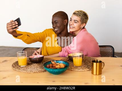 Multiethnic couple taking a selfie while having dinner Stock Photo
