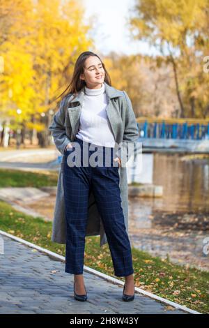 Full body portrait of a young beautiful brunette girl in gray coat Stock Photo