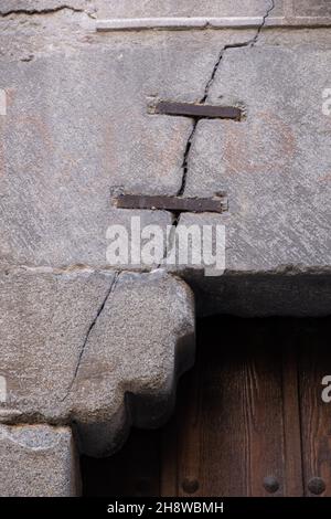 Metal staple to repair a crack in a stone wall. Vertical image Stock Photo