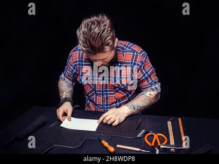 Leather cutter cutting out leather goods in his workplace Stock Photo
