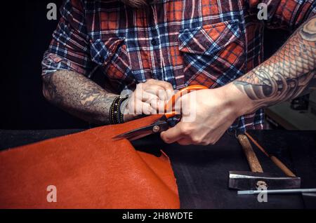Man working with leather using crafting scissors Stock Photo