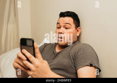 Hispanic male using the smartphone and looking surprised Stock Photo