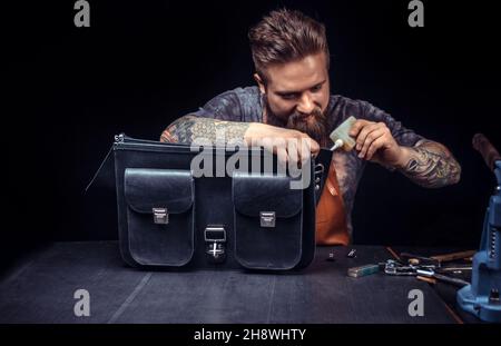 Craftsman working with leather processing a leather workpiece at a workshop Stock Photo
