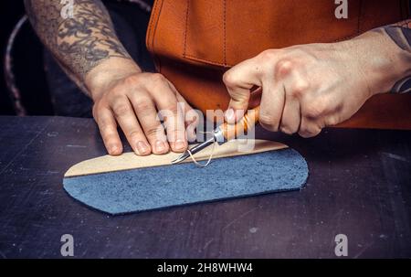 Artisan performing leatherwork on a new product piece Stock Photo