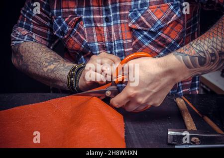 Leather Artisan cutting out leather goods in his leather studio Stock Photo