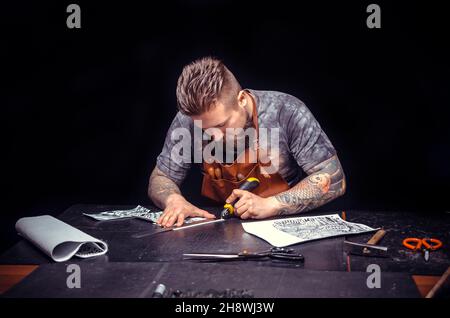 Professional Leather Worker cuts out leather goods Stock Photo