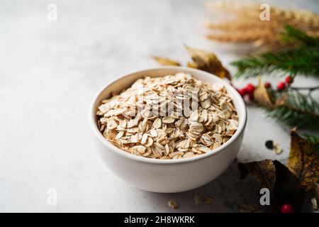 Old fashioned rolled oats in a white bowl on holiday background, selective focus Stock Photo