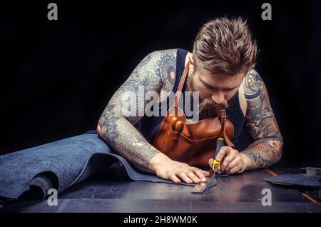 Man working with leather processes a workpiece from leather in the place of work Stock Photo
