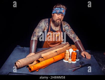 Artisan of leather works with leather at workplace Stock Photo