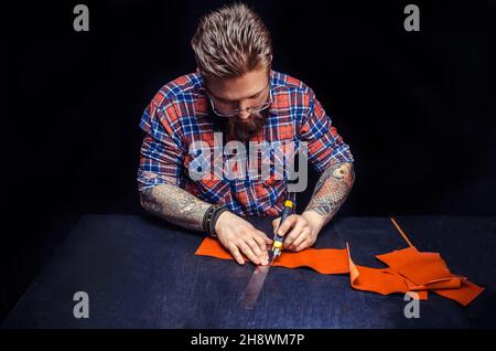 Worker of leather producing leather workpiece in the work area Stock Photo